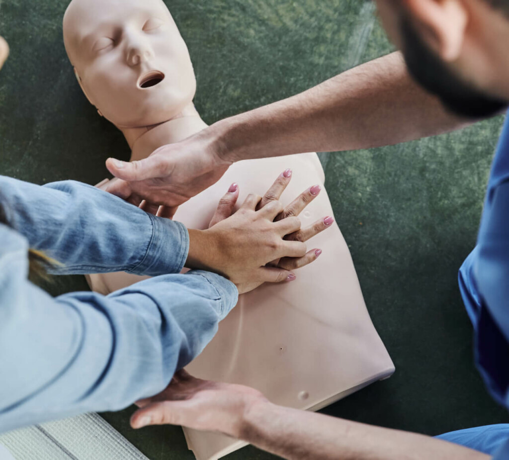 Two individuals practicing cpr on a training mannequin.