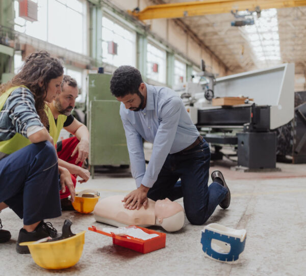 First aid training session in progress within an industrial setting.