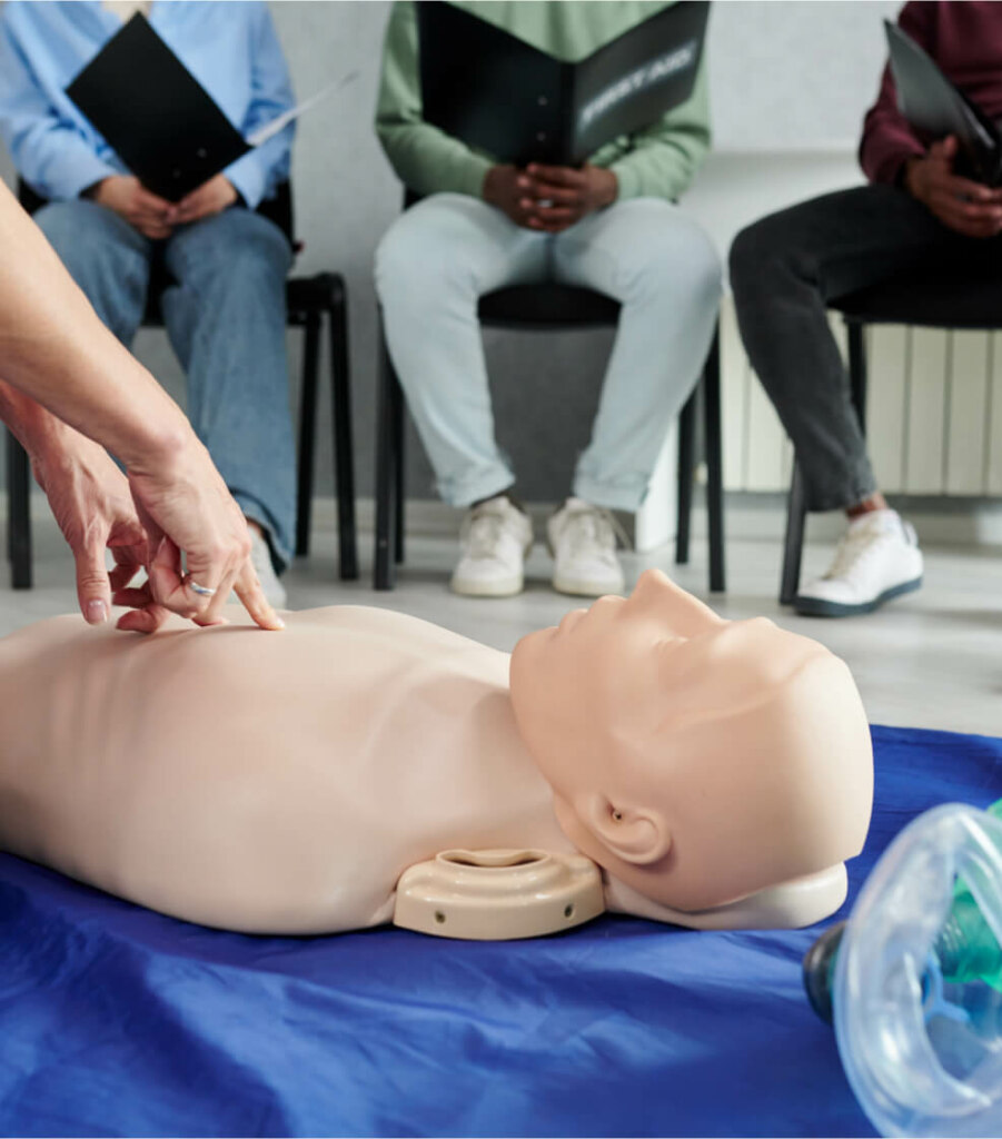 A CPR training session focused on Advanced Resuscitation, with a participant practicing on a mannequin while others observe.
