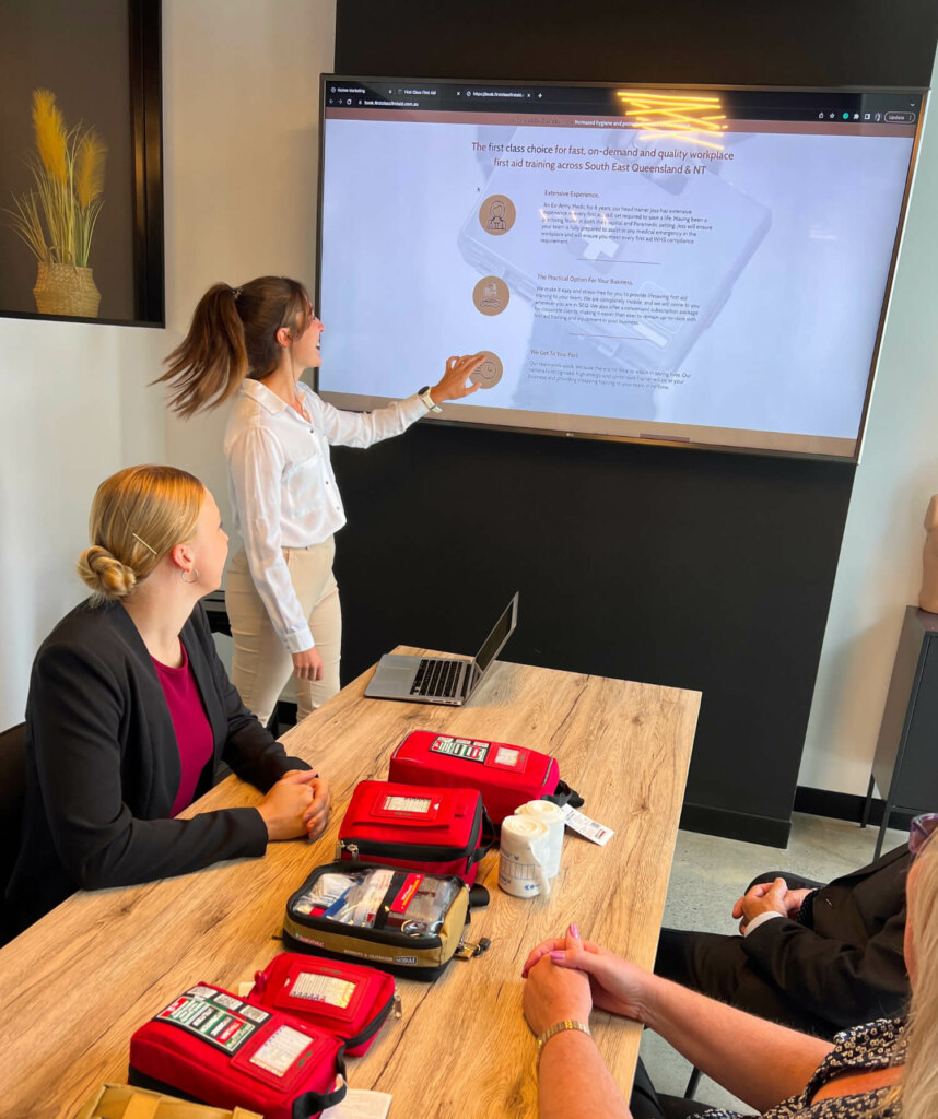 A presentation in a modern office setting with one person pointing at a screen and others watching attentively.